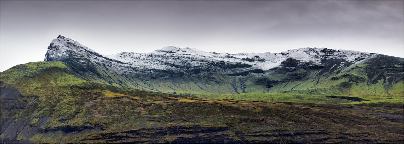 Schöner Kontrast zwischen die weiss verschneiten Bergen und das grüne Gras