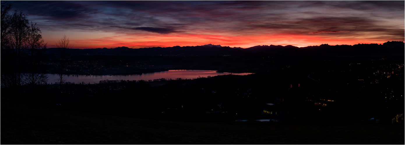 Februar. Der Himmel brennt am Horizont. Vorne der Greifensee